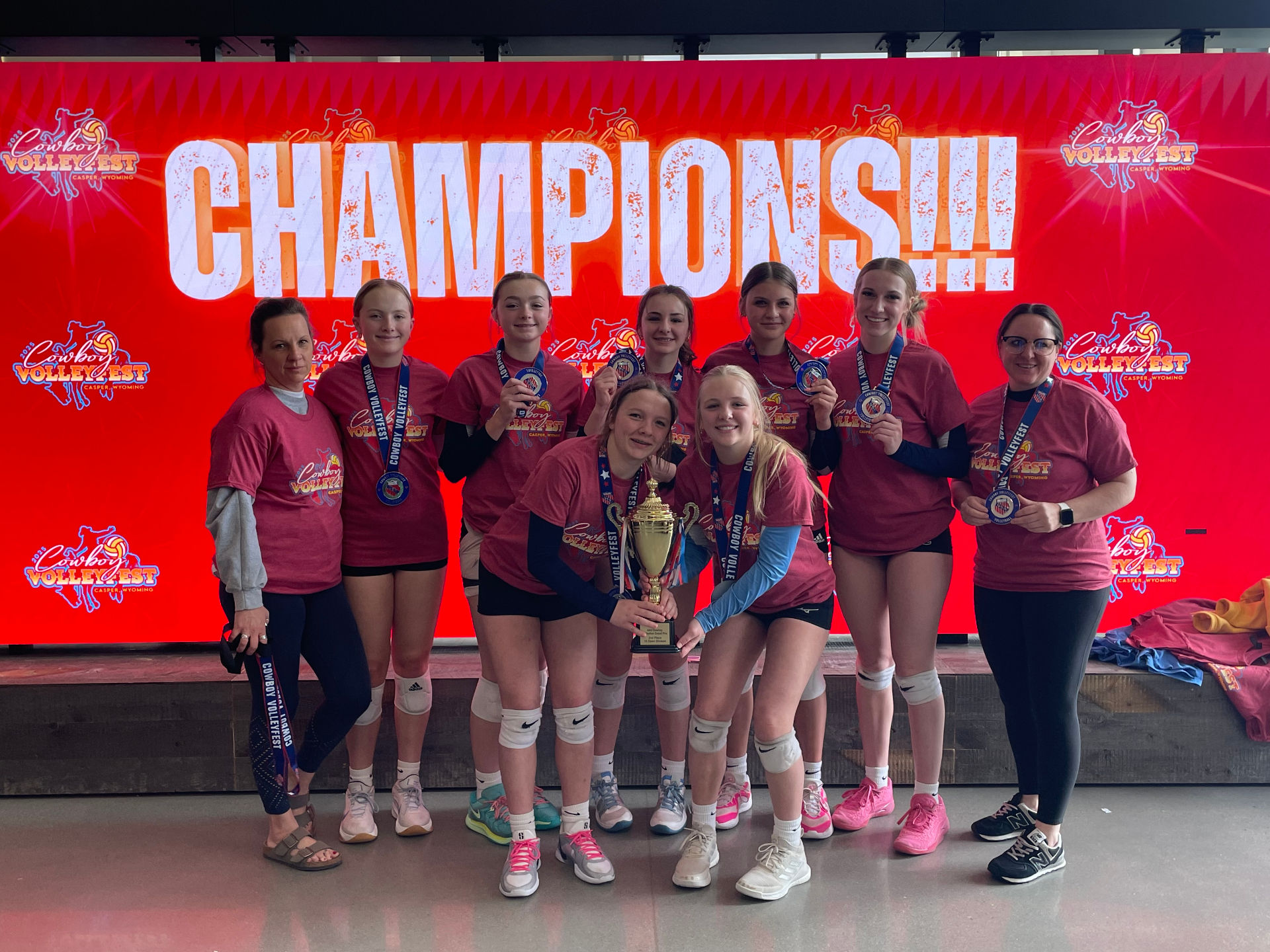 Zapata VBC team with trophy and medals in front of the Cowboy VolleyFest Champions screen